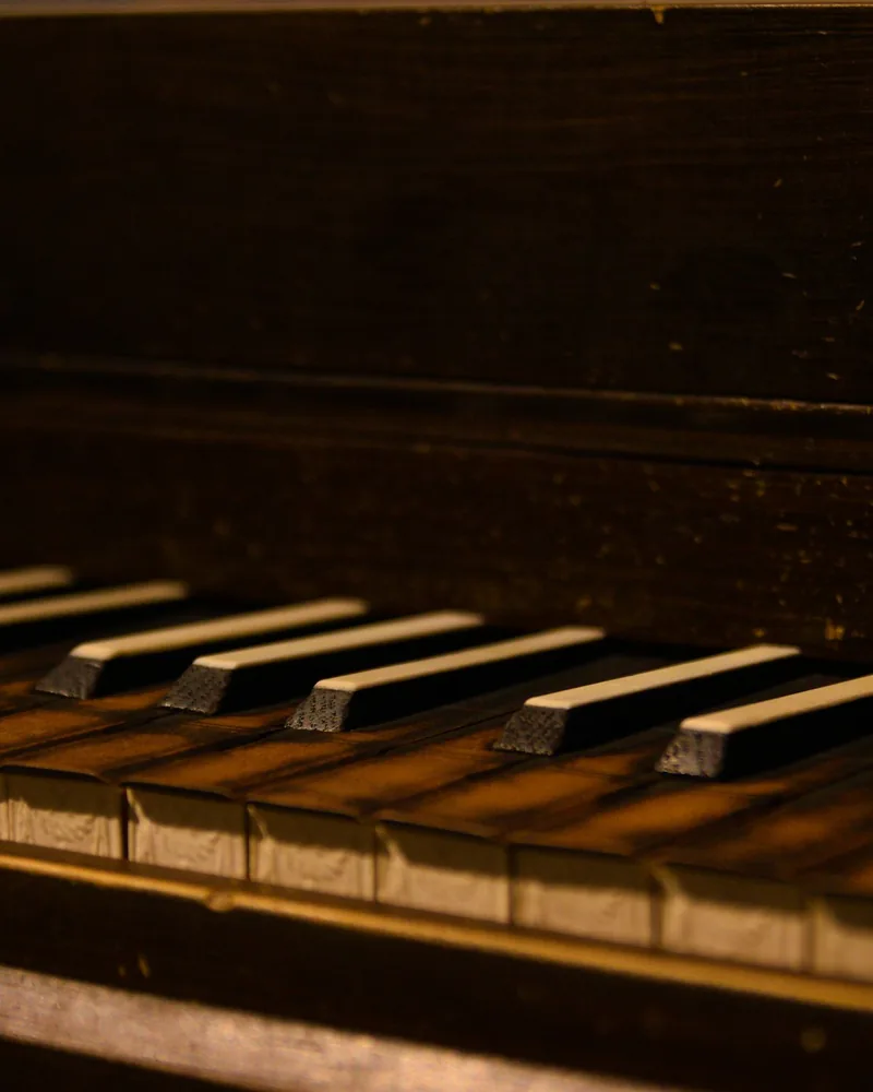 Detalle en primer plano de un teclado histórico con teclas de madera oscura y frentes labrados