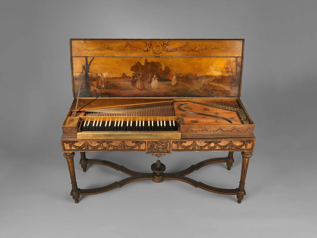 Instrumento histórico de teclado con la tapa levantada y decorada, encordado a la vista y puente curvo sobre la tabla armónica